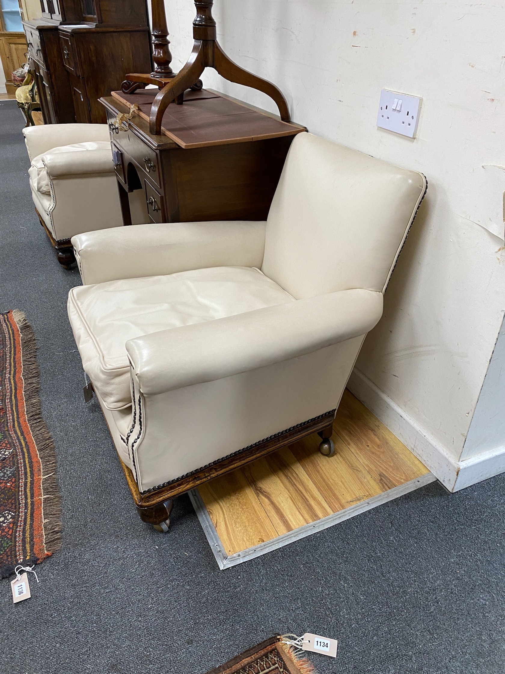 A pair of early 20th century oak cream leather club armchairs, width 76cm, depth 79cm, height 78cm